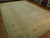 Angled view along the length of the rug, pale blue field meeting the sand coloured border