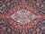 Close view of the ivory medallion on red ground surrounded by dense navy floral scrollwork