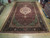 Rug laid flat on a warehouse wood floor, showing its full length and dark navy main border