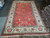 Great room sized coral area rug laid flat, green and blue accents throughout the field