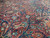 Close-up of rose red field showing blue and green floral vinework in wool pile
