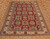 Angled view of hand-knotted wool Kazak rug, red field with ivory squares and stepped diamond motifs