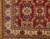 Close up corner detail of ivory border, navy rosettes and blue diamond medallion on red wool pile
