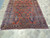 Angled floor view of antique wool Sarough area rug in a 7x11 living room size