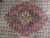 Close-up of the brick red lobed medallion with navy core and 4 gold cartouches