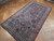 5'6" x 9'7" antique Persian tribal rug at an angle, serrated diamond lattice and ivory border