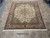 8' x 9' Persian Tabriz rug photographed flat on stone floor with ivory fringe ends