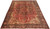 Angled floor view of hand-knotted Persian Heriz area rug showing navy border and geometric medallion