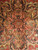 Salmon and navy geometric medallion detail with palmettes, hooked vines and ivory outlines at rug center