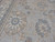 Close up of hand-knotted wool pile showing blue rosettes, taupe leaves and fine brown outlining