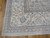 Corner detail with ivory main border, blue guard stripes and gray selvage over hardwood floor