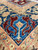 Close view of the blue main border with red hooked vase motifs and salmon guard stripes