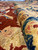 Rolled fold across the border, saffron wool and blue palmettes with the red field beyond