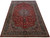 Angled 10'4" x 16'5" oversize Isfahan rug showing red field, navy border and ivory guard stripes