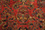 Close-up of hand-knotted wool pile: gold vase, navy leaves and rosettes on crimson ground