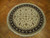 Ivory round wool and silk rug displayed on herringbone parquet floor in warm daylight
