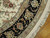 Black main border detail with floral vines, sage guard stripes and hand-tied ivory fringe