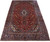 Angled display of the 9'6" x 16'1" Kashan rug showing red field and navy border