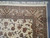 Corner detail showing camel beige border, cartouche motifs, ivory fringe and dense wool and silk weave