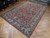 Angled floor view showing wool pile, ivory main border and navy vine work of Tabriz