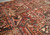Close-up of hand-knotted wool pile showing salmon, sage green and ivory geometric motifs