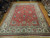 Oversize 11x14 hand-knotted Persian rug photographed lengthwise showing ivory border and dense red field