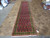 Long wool runner displayed on travertine showroom floor showing green border and repeating boteh motifs