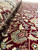 Folded pile detail revealing silk highlights with rose and cream flowers across the deep burgundy ground