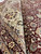 Ivory main border and wine red floral field seen together where the rug is folded back