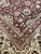 Close-up corner showing burgundy field, sage green palmettes and multiple ivory guard borders in fine wool