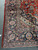 Corner of the Kashan rug showing navy main border, salmon palmettes and clean ivory fringe