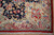 Corner close-up showing ivory spandrel, sage guard stripe, red outer band and clean fringe