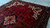 10 x 13 Persian rug laid on concrete floor showing red field, ivory corners and dense pile