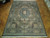 Multi-color traditional area rug displayed on herringbone parquet floor showing ivory fringe and dark navy border