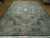 Angled floor view of large 10x14 hand-knotted Oriental rug with diamond lattice panels and floral border