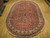 7'11" x 10'7" oval hand-knotted wool rug displayed on light wood showroom flooring