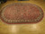 Angled full length view of the 8x11 oval Sarouk design rug showing border detail