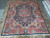 Signed 1970s Persian wool rug laid on stone tile showing full navy and coral design