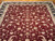 Close view of burgundy field covered in ivory palmettes and olive green vine scrolls, hand-knotted wool