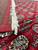 Folded corner revealing ivory cotton fringe, plain red end skirt and dense Bokhara field pattern