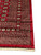 Wide corner view of the many borders framing the red field, hand-knotted in Pakistan