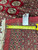 Inventory tag and steel tape measure resting on the border of this hand-knotted Bokhara rug