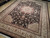 Angled showroom view of the black and ivory medallion rug showing dense floral field detail