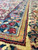 Low angle on blue border and gold vine stripe, showing plush hand-knotted wool pile