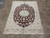 Burgundy and cream Persian Nain area rug photographed from above on stone tile in showroom