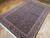 Angled view of black and rust wool and silk Tabriz rug on herringbone wood flooring