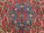 Close-up of navy blue central medallion with turquoise arabesques and palmettes on red wool and silk pile