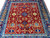 All-over floral field of golden palmettes, blue rosettes and brown vine scrolls on deep red