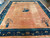 Deep blue border with ivory peony blossoms frames the salmon field of this antique rug