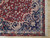Corner detail showing navy spandrel, ivory floral guard border and clean cotton fringe